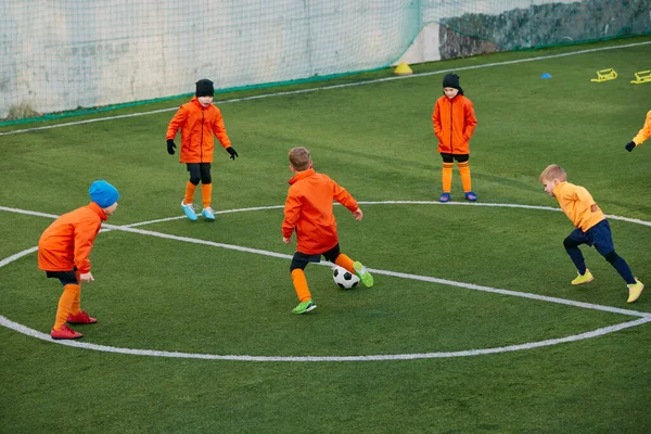 Competition. Group of boys, children, football players in uniform in motion, playing, training on field outdoors. Concept of sport, childhood, active lifestyle, hobby, sport club