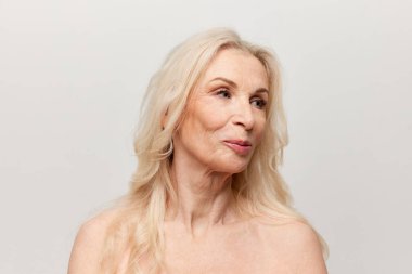 Beauty of age. Portrait of beautiful middle-aged, mature woman with well-kept natural skin posing over grey background. Concept of natural beauty, face skin care, cosmetology and cosmetics, health