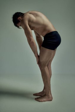 Relief, strong body shape. Young man with muscular body posing shirtless in black underwear over studio background. Concept of mans beauty, sportive and healthy lifestyle, fashion
