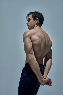 Relief, strong, healthy back. Muscular young man posing shirtless in underwear over blue studio background. Concept of mans beauty, sportive and healthy lifestyle, fashion, strength