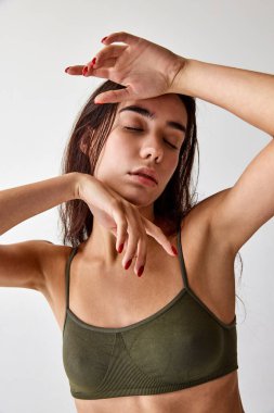 Tenderness. Portrait of beautiful young brunette girl posing in underwear over grey studio background. Concept of natural beauty, femininity, wellness, body and skin care, fitness
