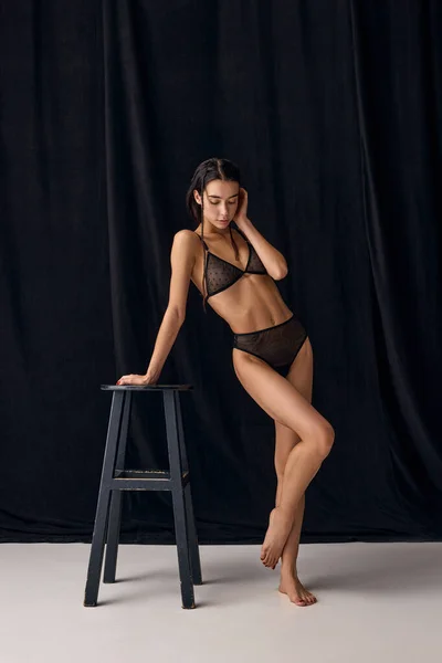 Sensuality and femininity. Portrait of beautiful young slim girl in underwear posing over black studio background. Concept of natural beauty, tenderness, femininity, body care and fitness