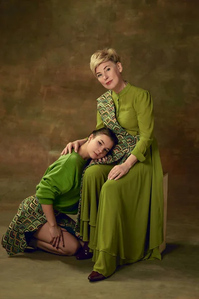Respect and support. Beautiful middle-aged woman, mother with young girl, daughter posing over vintage studio background. Concept of motherhood, family, mothers day, love, emotions, relationship