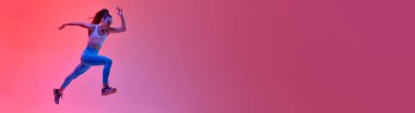 Dynamic image of young sportive girl, professional runner, athlete running on pink studio background in neon light. Concept of sportive lifestyle, health, endurance, motion. Banner. Copy space for ad