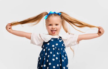 Happiness. Beautiful cute little girl, child in retro style dress smiling, posing against grey studio background. Concept of childhood, game, emotions, activity, leisure time, retro style, fashion.