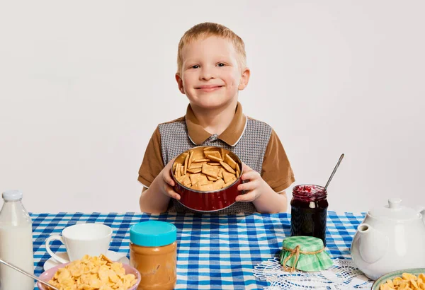 Szczęśliwy Pozytywny Chłopiec Dzieciak Siedzący Przy Stole Jedzący Śniadanie Szarym — Zdjęcie stockowe