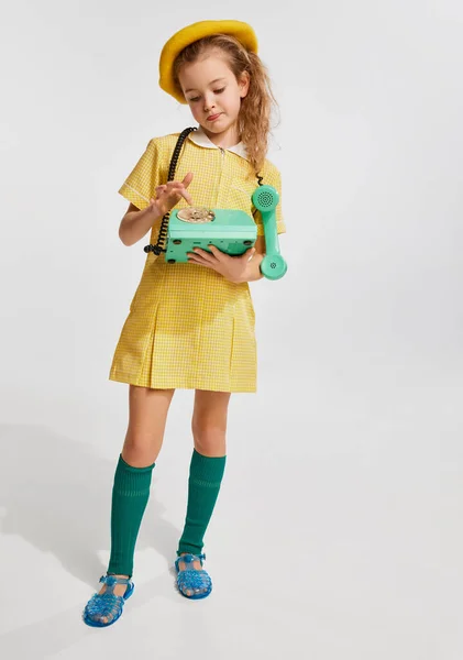 漂亮的小女孩 穿着复古的黄色连衣裙 拿着电话 在灰色的工作室背景下摆姿势 闲暇时间 复古风格 时尚的概念 — 图库照片