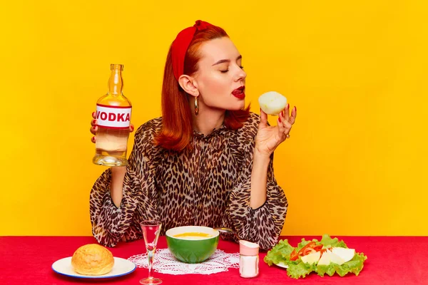 食品流行艺术摄影 美丽的红头发女人在黄色的背景下坐在桌旁吃饭 和洋葱一起喝伏特加 互补的颜色 文字的复制空间 — 图库照片
