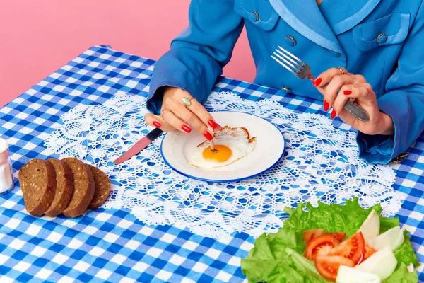 Top view image of female hand putting cigarette into egg yolk on fried eggs at checkered retro tablecloth. Food pop art photography. Creativity, art. Complementary colors. Copy space for ad, text