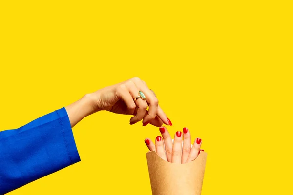 Fast food. Female fingers instead of fries into packaging against yellow studio background. Surrealism and creativity. Food pop art photography. Complementary colors. Copy space for ad, text