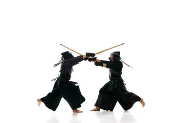 Dövüşçüler. İki adam, profesyonel kendo atletleri, beyaz stüdyo geçmişine karşı bambu shinai kılıcı ile kask eğitimi almış üniformalılar. Dövüş sanatları, spor, Japon kültürü, aksiyon, hareket kavramı