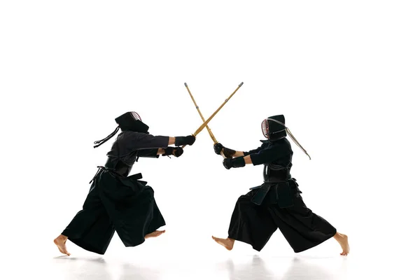 白スタジオを背景に竹刀で稽古をするプロの剣道選手2人のダイナミックなイメージ スポーツ 日本文化 アクション 動きの概念 — ストック写真