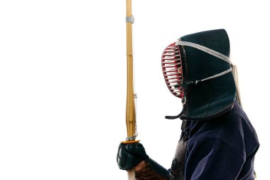 Yan görüş. Beyaz stüdyo arka planına karşı Shinai kılıcıyla poz veren profesyonel kendo sporcusu bir adamın portresi. Dövüş sanatları, spor, Japon kültürü, aksiyon ve hareket kavramı