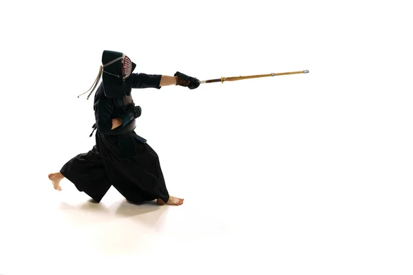 プロの剣道選手で 白地の稽古場を背景に竹刀で兜の稽古をしている男 スポーツ 日本文化 アクション 動きの概念 — ストック写真