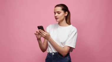 Gayri resmi giyinmiş güzel bir genç kız telefonla yayın yapıyor. Pembe stüdyo geçmişine karşı şaşkın ve pozitif duygular gösteriyor. Başarı. İş, iletişim, eğitim, satış, bahis konsepti