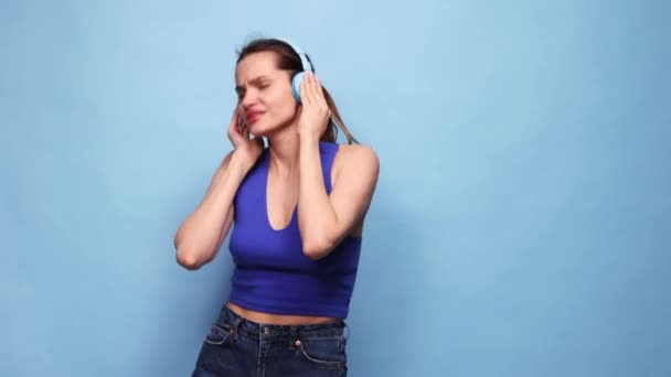 Szczęśliwa Aktywna Młoda Dziewczyna Emocjonalnie Słuchająca Muzyki Słuchawkach Tańcząca Niebieskim — Wideo stockowe