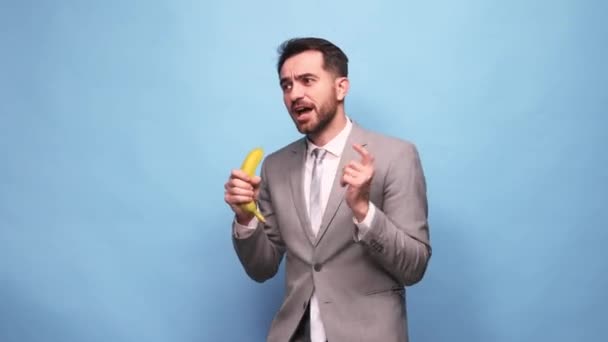 Fröhlich Fröhlicher Mann Geschäftsmann Dienstanzug Emotional Singend Bananenmikrofon Vor Blauem — Stockvideo
