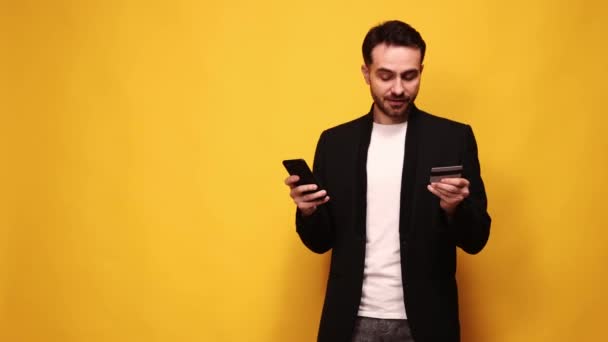 Jóképű Fiatalember Elegáns Fekete Dzsekiben Online Vásárlás Mobiltelefonnal Hitelkártyával Sárga — Stock videók
