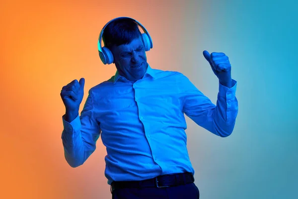 Felnőtt Középkorú Férfi Portréja Amint Fejhallgatóban Zenét Hallgat Neonfényben Gradiens — Stock Fotó