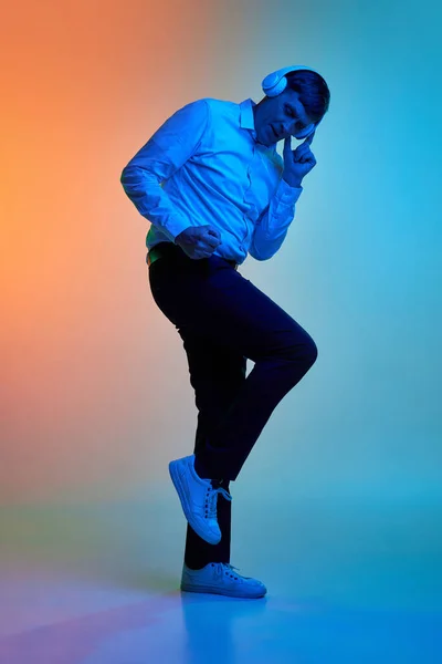 完整的中年男人肖像 用耳机听音乐 在霓虹灯下在渐变的蓝色橙色背景上跳舞 情绪的概念 生活方式 面部表情 — 图库照片