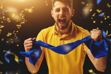 Pozitif olmak. Genç adam, spor taraftarı Ukrayna 'nın favori futbol takımını konfeti ile neşelendiriyor. Spor anlayışı, boş zaman, duygular, hobi ve eğlence