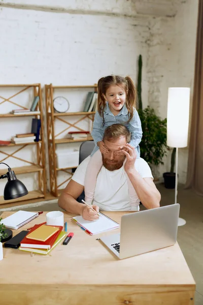 大人の男性 父親はテーブルに座って 小さな就学前の娘が肩に座っている自宅でノートパソコンでリモートで作業しています 子供時代 フリーランスの仕事 内務省の概念 — ストック写真
