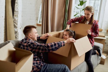 Oyuncu bir ebeveyn ve küçük bir kız. Eğleniyorum. Genç mutlu aile, kadın, erkek ve çocuk bir sürü karton kutuyla yeni bir daireye taşınıyor. Taşınma konsepti, gayrimenkul, aile, yeni hayat