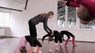 Küçük kızlar, çocuklar, içeride koçluk eğitimi alan jimnastikçiler. Jimnastik köprüsü egzersizi yapıyorum. Spor yaşam tarzı kavramı, çocukluk, eğitim, sağlık, profesyonel spor.
