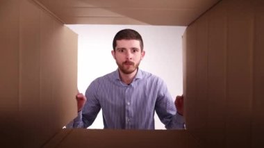 Yanlış, yanlış teslimat. Genç adam paketleri açıyor, karton kutuyu açıyor ve tatmin olmamış bir yüzle içine bakıyor. Alışveriş, dağıtım, duygu ve yüz ifadesi kavramı