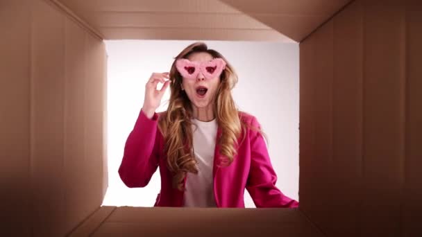 スタイリッシュなピンクのジャケットの若い女の子は 楽しさと興奮した顔を持つ段ボール箱を開きます 成功したショッピング 食品の配達 買い物 感情や表情の概念 — ストック動画