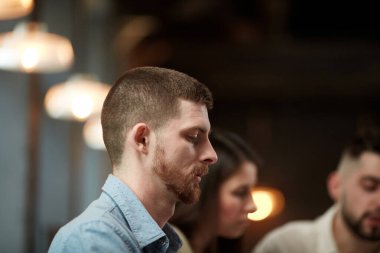 Genç ve ciddi bir adamın yakın plan görüntüsü, ofiste iş arkadaşlarıyla görüşen bir çalışan. İnsanlarla geçmişi bulanık. İş anlayışı, takım çalışması, kariyer geliştirme, beyin fırtınası