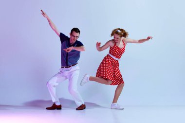 Renkli kostümler içinde şık bir kız ve erkek gradient mavi mor stüdyo arka planına karşı retro dansı yapıyor. Sanat anlayışı, retro tarzı, hobi, parti, eğlence, hareketler, 60 'lar, 70' ler kültürü