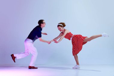 Retro dans stilleri. Genç aktif bir çift, kadın ve erkek eğleniyor. Mor renkli gradyan stüdyo arka planında dans ediyor. Sanat anlayışı, retro tarzı, hobi, parti, eğlence, hareketler, 60 'lar, 70' ler kültürü