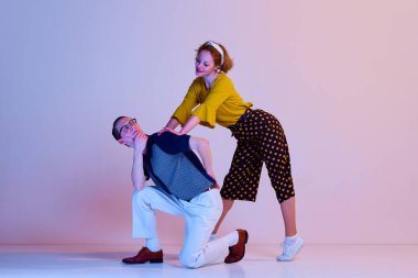 Duygusal genç çift, şık giyinen erkek ve kadın. Gradyan pembe mor stüdyo arka planına karşı retro dans ediyorlar. Sanat anlayışı, retro tarzı, hobi, parti, eğlence, hareketler, 60 'lar, 70' ler kültürü