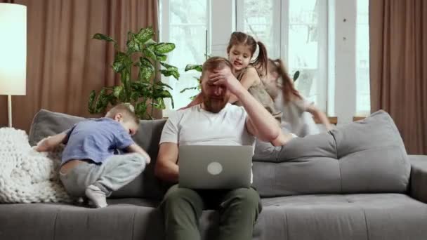 太吵了男人 父亲坐在沙发上 和他的孩子们在他身边大声玩耍 自由职业 远程工作 情感的概念 — 图库视频影像