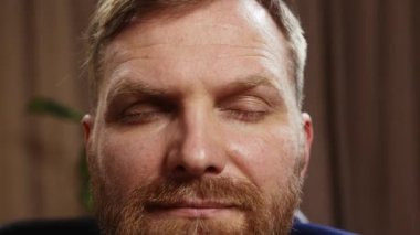 Sakallı adamın yakın plan görüntüsü, iş adamı gözlerini açıyor, sakin ve rahat hissediyor. Uzaktan evde çalışıyor. Babalık kavramı, çocukluk, serbest meslek, uzak çalışma, duygular