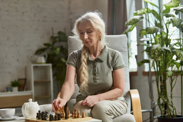 Красивая Пожилая Женщина Отставке Сидит Стуле Внимательно Играет Шахматы Внутренний — стоковое фото