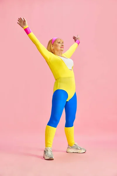 운동복을 따뜻하게 준비하고 나이든 여성의 분홍색 스튜디오 배경에 배치되어 있습니다 — 스톡 사진