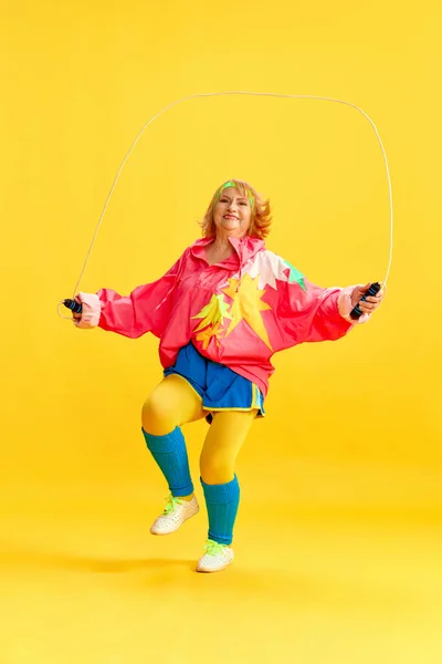 Fröhliche Seniorin Buntem Uniformtraining Seilspringen Posiert Vor Gelbem Studiohintergrund Konzept — Stockfoto