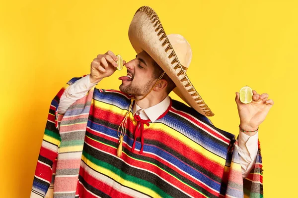 Jovem Poncho Colorido Sombrero Espremendo Limão Sua Língua Posando Contra — Fotografia de Stock