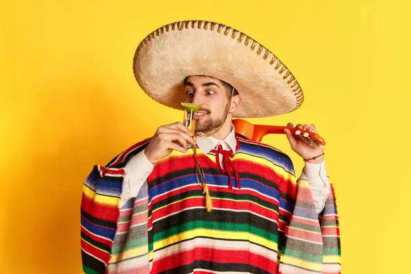 Młody Pogodny Mężczyzna Kolorowym Ponczo Sombrero Pozujący Wąchający Tequilę Limonką — Zdjęcie stockowe