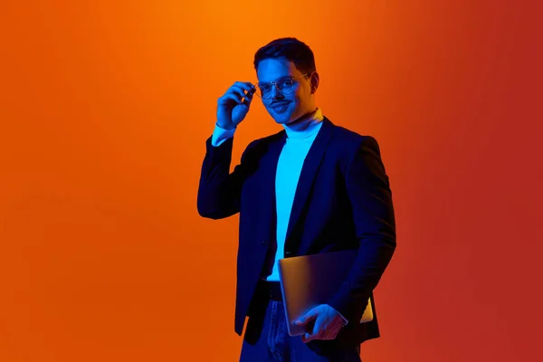 Портрет Молодого Позитивного Человека Куртке Очках Позирующего Ноутбуком Фоне Оранжевой — стоковое фото