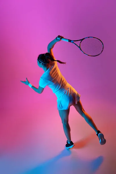 ネオンを背景にピンクのスタジオを背景にした均一なトレーニングで女性テニス選手のトップバックビューイメージ ボールを出す プロスポーツ 行動の概念 — ストック写真