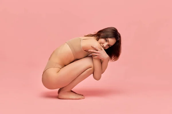 女性らしさだ ピンクのスタジオの背景に対してポーズをとってベージュの下着で魅力的でかわいい 若い女の子の肖像画 スリムな体だ 身体と肌のケア フィットネス ウェルネスの概念 — ストック写真