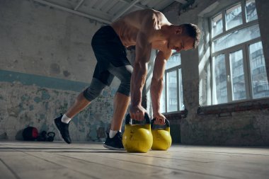 Genç, yakışıklı, kaslı, güçlü, formda vücut antrenmanı yapan, gündüz vakti ağırlık kaldıran bir adam. Günlük antrenman. Spor yaşam tarzı, vücut bakımı, fitness, hobi, sağlık
