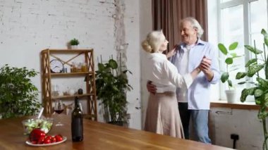 Mutlu, olgun, yaşlı bir çift, emekli bir adam ve bir kadın evde güzel vakit geçiriyorlar, dans ediyorlar, yemek yiyorlar, şarap içiyorlar. Aile kavramı, ilişki, emeklilik, yaşam tarzı