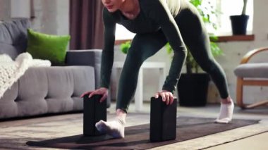 Spor koçu, genç esnek, sportif kız eğitimi evde yoga yapıyor ve yoga bloklarıyla esneme egzersizleri yapıyor. Güçlü vücut. Sportif ve sağlıklı yaşam tarzı kavramı, sağlık, bakım.
