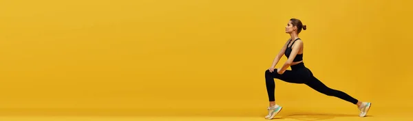 柔韧的年轻姑娘 身材苗条 穿着舒适的运动服 伸展身体 在黄色的背景下训练 积极的生活方式 健身观念 班纳广告的复制空间 — 图库照片