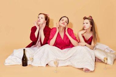 Cilde özen gösteriyorum. Pijama partisinde güzel kızlar battaniyenin altında oturup maske takıyor. Birlikte eğleniyoruz. Gençlik kavramı, duygular, güzellik, arkadaşlık, parti, rahatlama