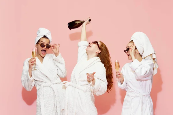 ピンクのスタジオを背景にお祝いと楽しさを持って シャンパンを飲んでバスローブで3人の幸せ 美しい女の子 若者の概念 美しさ パーティー リラクゼーション — ストック写真